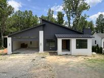 Modern home featuring a dark gray exterior, white brick accents, an attached garage, and metal roof at 269 Deer Tail Ln # 44, Fuquay Varina, NC 27526
