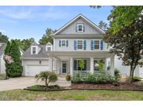 Charming two-story home features a welcoming front porch with blue shutters and manicured landscaping at 429 Marsh Landing Dr, Holly Springs, NC 27540