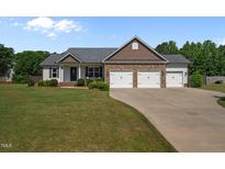 Charming single-story home boasts a three-car garage and well-manicured lawn at 45 Hawley Ridge Dr, Dunn, NC 28334