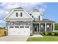 Charming two-story home with stone accents, two-car garage, and manicured lawn at 4504 Beckel Rd, Willow Springs, NC 27592