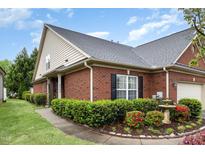Charming brick home featuring manicured landscaping, green lawn, black shutters, and a delightful water fountain at 8005 Crookneck Dr, Angier, NC 27501