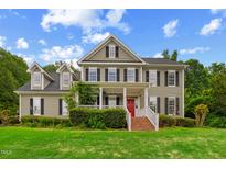 Charming two-story home with a well-manicured lawn, inviting porch, and a vibrant red front door at 809 Parkridge Dr, Clayton, NC 27527