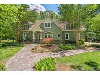 Charming two-story home featuring a stone walkway and beautifully landscaped front yard surrounded by mature trees at 8232 Glynmorgan Way, Chapel Hill, NC 27516