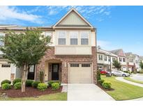 Charming townhome boasts a brick facade, attached garage, and landscaped front yard with a blue sky at 2211 Sweet Annie Way, Wake Forest, NC 27587