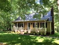 Charming home with a rocking chair front porch surrounded by mature trees and lush lawn at 2603 Red Pine Rd, Hillsborough, NC 27278