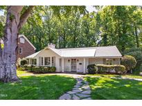 Charming white brick home with manicured landscaping, stone walkway, and a metal roof at 3028 Rothgeb Dr, Raleigh, NC 27609