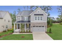 Charming two-story home featuring stone accents, a gray color palette and a manicured front lawn at 3217 Armeria Dr, Apex, NC 27502