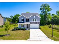 Charming two-story home with gray siding, stone accents, well-maintained lawn, and an inviting front porch at 325 Porterfield Dr, Youngsville, NC 27596