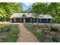 Charming home exterior with metal roof, landscaped yard, and inviting front porch with rocking chairs at 4022 Tecolote Way, Hillsborough, NC 27278