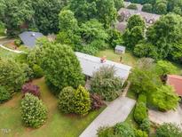 Aerial view of a home with mature trees, a long driveway, and a charming shed in the backyard at 4832 Brookhaven Dr, Raleigh, NC 27612