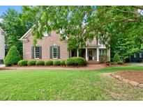 Well-manicured brick home featuring a lush green lawn, mature trees, and a welcoming brick walkway at 5217 Roswellcrest Ct, Apex, NC 27539