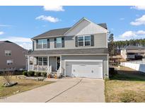Charming two-story home with a front-facing two-car garage, a porch with a white railing, and manicured landscaping at 59 Nevada Ct, Clayton, NC 27527