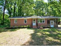 Charming brick home featuring a well-maintained lawn and a screened in porch in a tranquil, wooded setting at 6017 Whitaker Ln, Raleigh, NC 27603