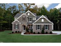 Beautiful two-story home with brick and stone exterior, complemented by a lush green lawn and mature trees at 6104 Hope Farm Ln # 18, Wake Forest, NC 27587