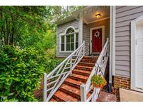 Charming front entrance with brick steps, white railing, and vibrant green foliage at 8 Wexford Dr, Durham, NC 27713