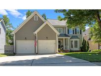 Charming two-story home featuring a two-car garage, manicured lawn, and a welcoming front porch and an American flag at 8724 Deerland Grove Dr, Raleigh, NC 27615