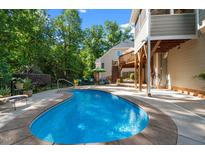 Backyard with a kidney shaped pool, patio and wooden deck in a tranquil setting at 8724 Deerland Grove Dr, Raleigh, NC 27615