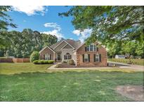 Charming brick home boasts a manicured lawn, black shutters, and lush landscaping at 95 Live Oak Dr, Louisburg, NC 27549