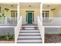 Inviting front porch with white railings, hanging porch swings, and a vibrant green front door at 101 Rainbow Dr, Carrboro, NC 27510