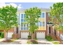 Charming townhome with brick facade, garage, and lush green trees on a sunny day at 1028 Summerhouse Rd, Cary, NC 27519
