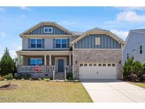 Charming two-story home with a combination of stone and shingle siding, complemented by a well-manicured lawn at 105 Blue Prince Trl, Holly Springs, NC 27540