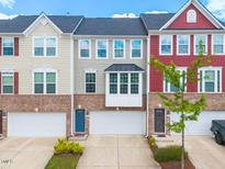 Charming multi-colored brick townhomes featuring attached garages and well-maintained landscaping at 114 Cross Country Way, Durham, NC 27703