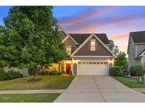 Charming home featuring a manicured lawn, two car garage, and stone and gray shingle exterior at 117 Woodlark Ln, Holly Springs, NC 27540