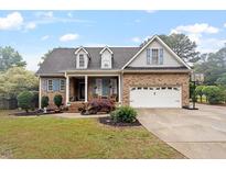 Charming brick home featuring a two-car garage, beautiful landscaping, and a lovely front porch at 151 Donnibrook, Fuquay Varina, NC 27526