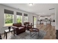 Bright living room featuring wood floors, large windows, and comfortable leather armchairs at 170 Creekhaven Dr, Angier, NC 27501