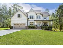 Charming two-story home featuring a covered porch, well-manicured lawn, and attached two-car garage at 1723 River Club Way, Franklinton, NC 27525