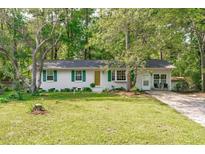 Charming single-story home featuring a brick facade, bright green shutters and lush landscaping at 1805 Holly St, Apex, NC 27502