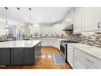 Bright kitchen featuring white cabinets, an island with a marble countertop, and stainless steel appliances at 205 Olive Field Dr, Holly Springs, NC 27540