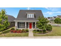 Charming home featuring a red front door, stone accents, a manicured lawn, and fresh landscaping at 2057 Big Falls Dr, Wendell, NC 27591