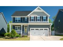 Charming two-story home with a gray exterior, stone accents, an attached two car garage, and a well manicured lawn at 3678 Horton Hill Dr, New Hill, NC 27562