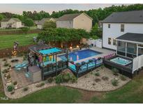 Aerial view of backyard pool area with bar, hot tub, fire pit, and lush landscaping at 60 Consella Way, Franklinton, NC 27525