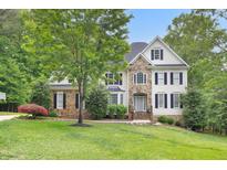 Beautiful home showcasing stone accents, a well-manicured lawn, and mature trees providing shade at 7000 Millstone Ridge Ct, Raleigh, NC 27614