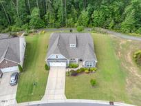 An aerial view of a home featuring beautiful landscaping, a two car garage, and mature tree coverage at 704 Long Lake Dr, Fuquay Varina, NC 27526