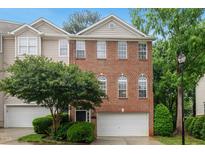 Charming brick townhome featuring a two-car garage and beautifully landscaped front yard at 7340 Doverton Ct, Raleigh, NC 27615