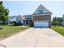 Charming two-story home featuring a stone accented facade, well-manicured lawn, and a double car garage at 90 Heathgreen Dr, Clayton, NC 27527