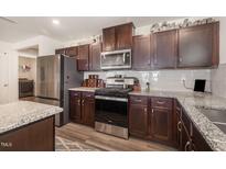 Features a range, microwave, granite countertops, tile backsplash and stainless steel refrigerator at 1012 Ringhill Bluff Dr, Durham, NC 27704