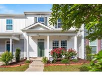 Charming townhome exterior with a covered porch, green door, and well-manicured landscaping at 1027 Myers Point Dr, Morrisville, NC 27560