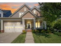 Inviting exterior view of a two-story home featuring a well-manicured lawn, two-car garage, and charming front porch at 121 Bridgegate Dr, Cary, NC 27519