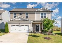 Charming two-story home featuring an attached garage, manicured lawn, and inviting entryway at 19 Cecina Ct, Clayton, NC 27527