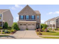 Charming two-story brick home featuring a two-car garage, well-manicured lawn, and colorful landscaping at 1904 Birdhouse Ln, Wake Forest, NC 27587