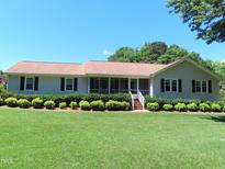 Charming ranch home featuring a well-manicured lawn, established shrubbery, and a screened front porch at 2000 Howson Rd, Raleigh, NC 27603