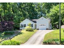 Charming home with a single-car garage, a driveway, and a yard surrounded by lush trees at 203 Needle Park Dr, Cary, NC 27513