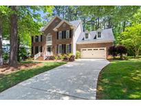 Charming brick home with a two-car garage and inviting front yard, nestled among mature trees at 206 Kettlebridge Dr, Cary, NC 27511