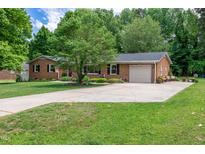 Charming one-story brick home featuring a well-maintained lawn, mature trees, and an attached garage at 2824 Blanche Dr, Burlington, NC 27215