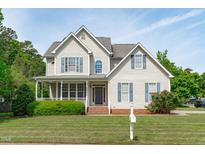 Charming two-story home featuring a welcoming front porch, blue shutters, and beautifully maintained landscaping at 6002 Whisperwood Dr, Durham, NC 27713