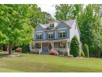 Charming blue two-story home with a welcoming front porch and well-manicured lawn surrounded by mature trees at 6509 Duncans Creek Ct, Fuquay Varina, NC 27526